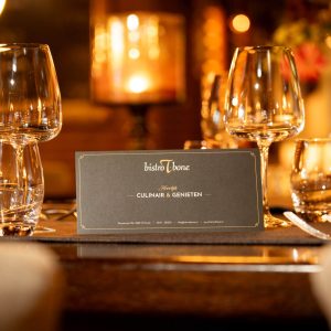 Geschenkbon van Bistro T-Bone op sfeervol gedekte restauranttafel met wijnglazen en warm kaarslicht