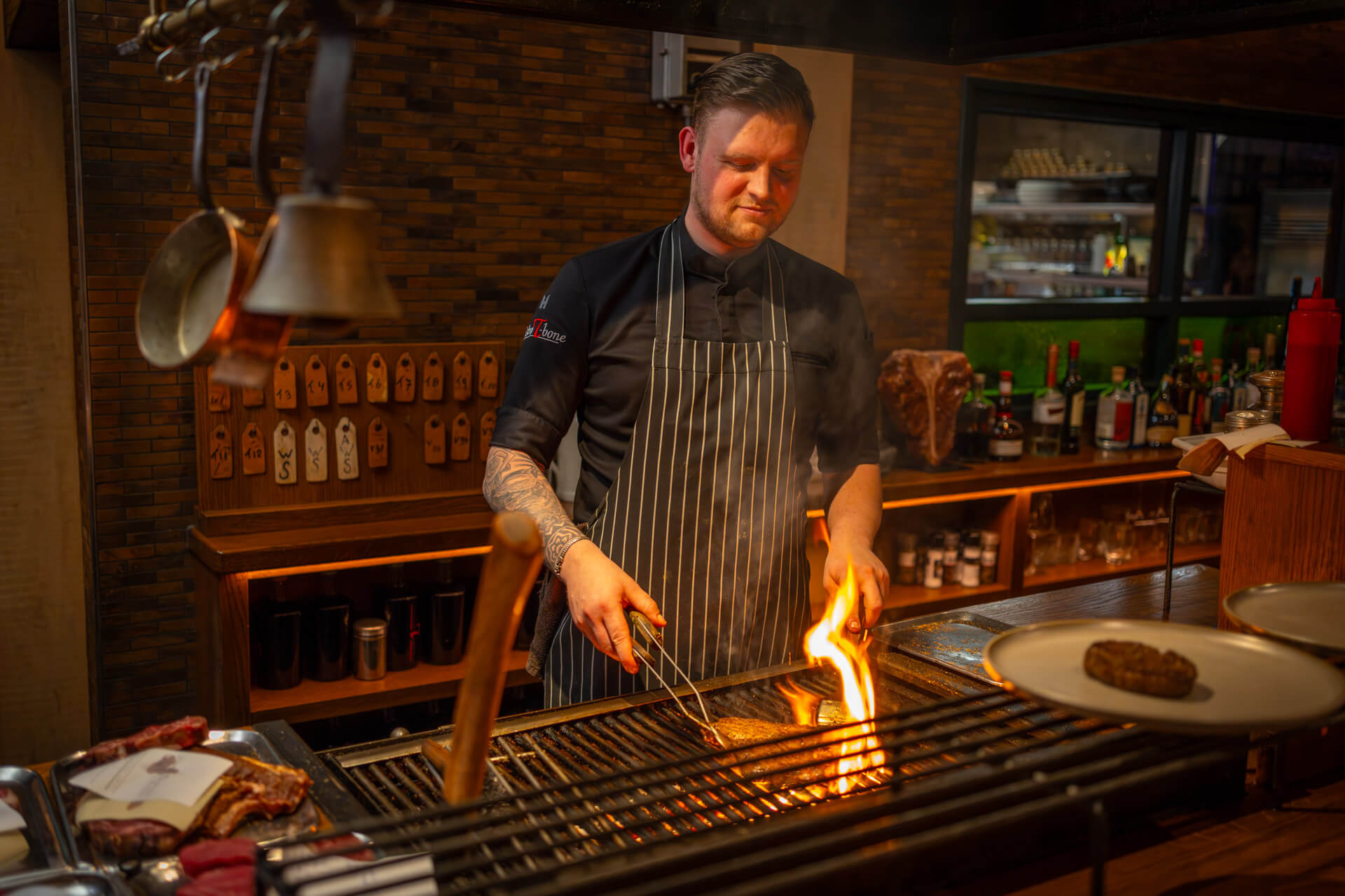 Kok grilt vlees op open vuur in de keuken van Bistro T-Bone voor restaurant vacature